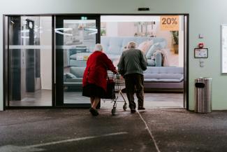 man in red shirt and black pants sitting on black and silver wheel chair by Claudio Schwarz courtesy of Unsplash.